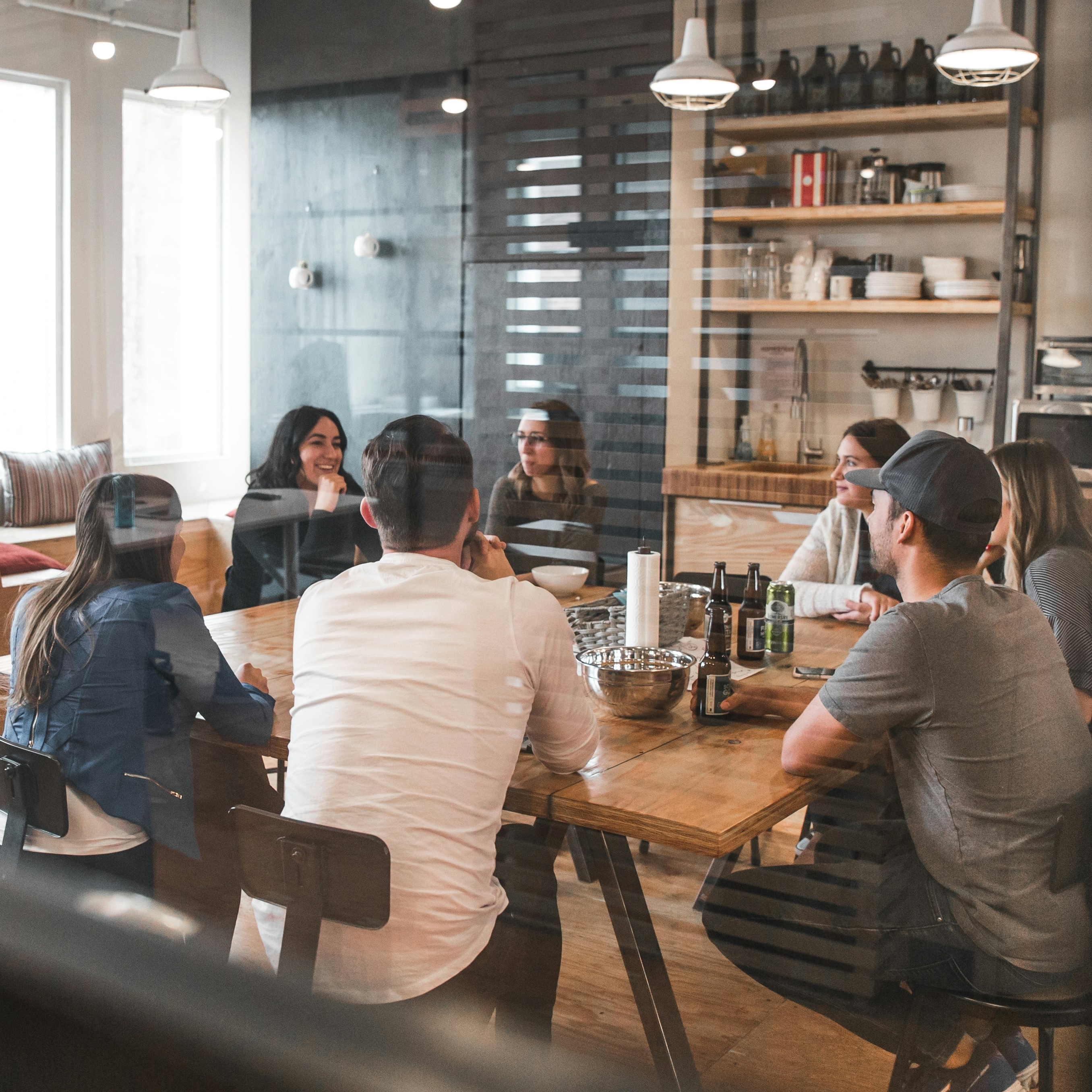 A group of adults talks around a table in a bright meeting space.