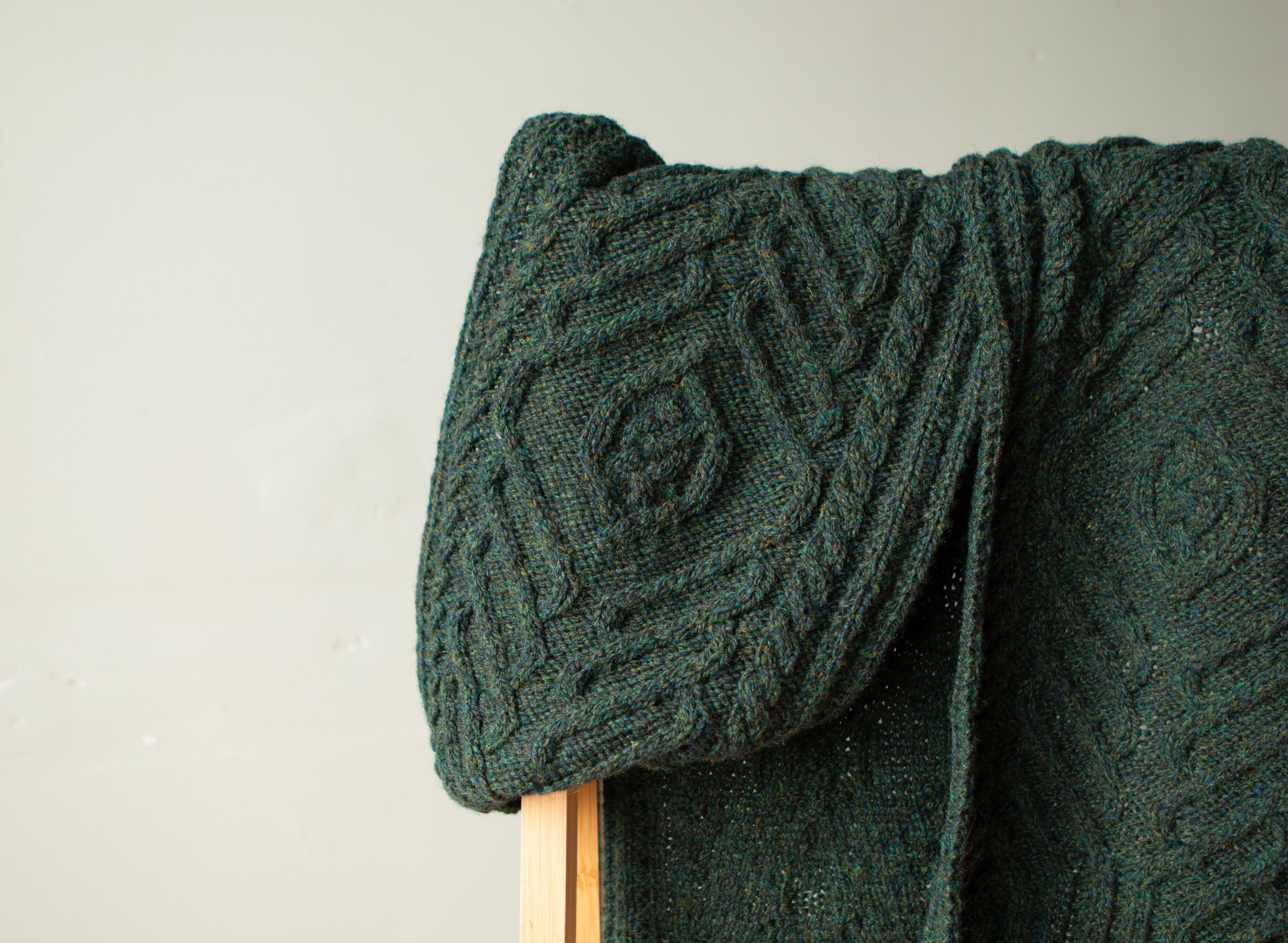 A hand-knit cabled scarf hung over a shelf.