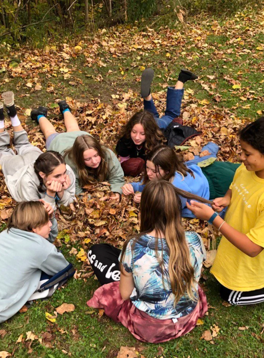 A group of adolescents sitting in a circle on autumn leaves