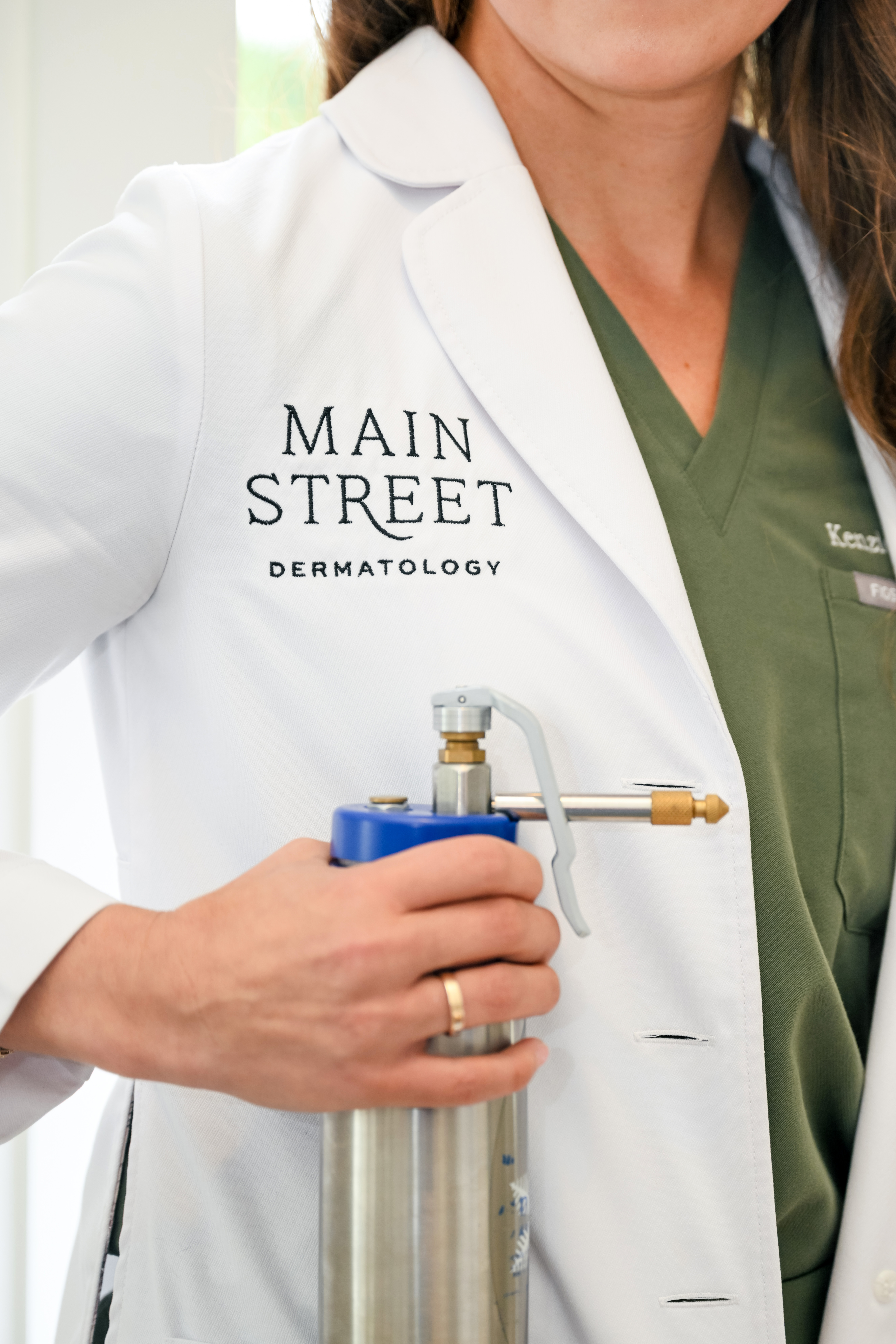 Main Street Dermatology provider in professional attire holding a cryotherapy (liquid nitrogen) spray device