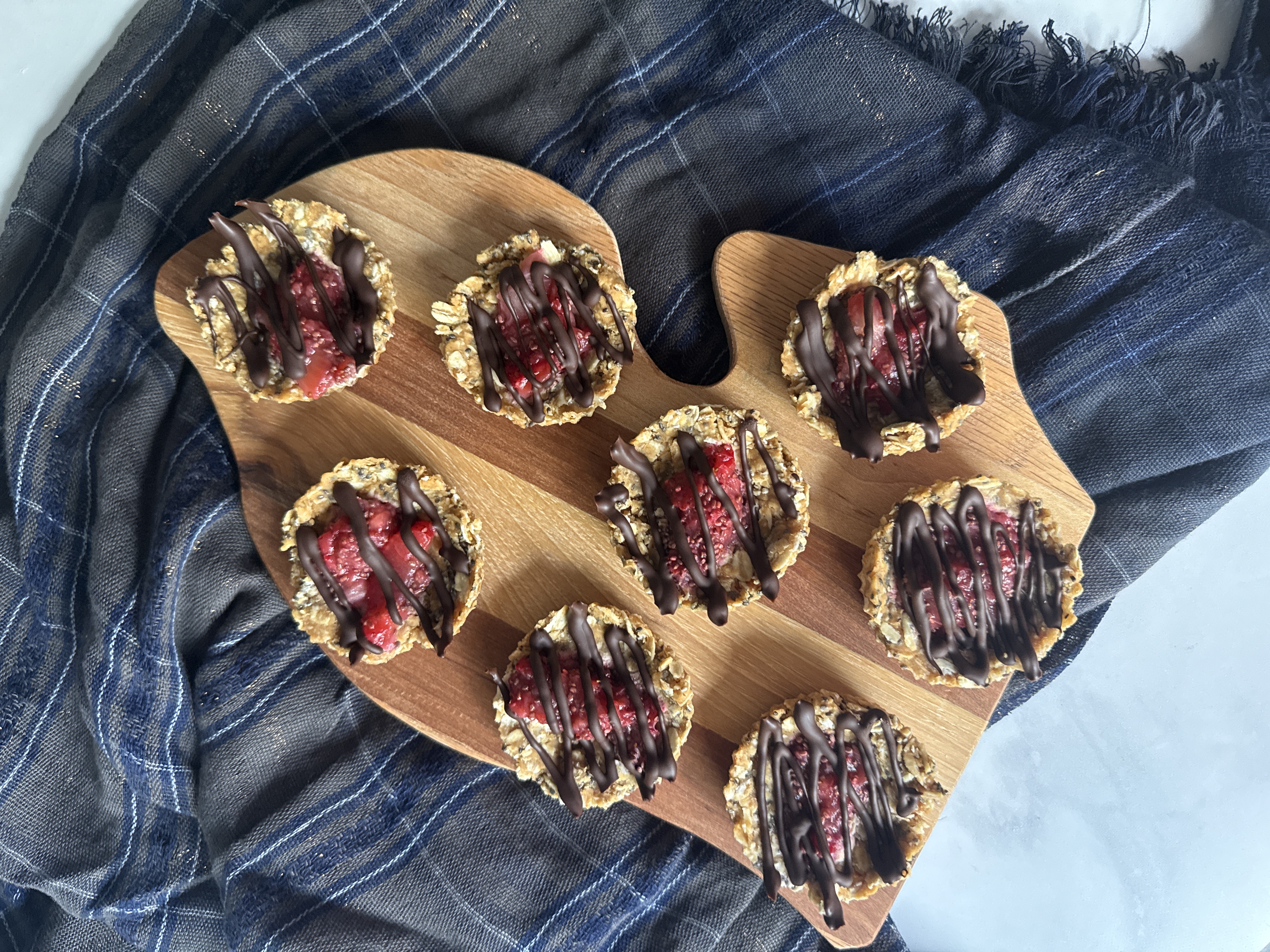 Michigan cutting board with chocolate strawberry dessert bites on blue cloth and marble table