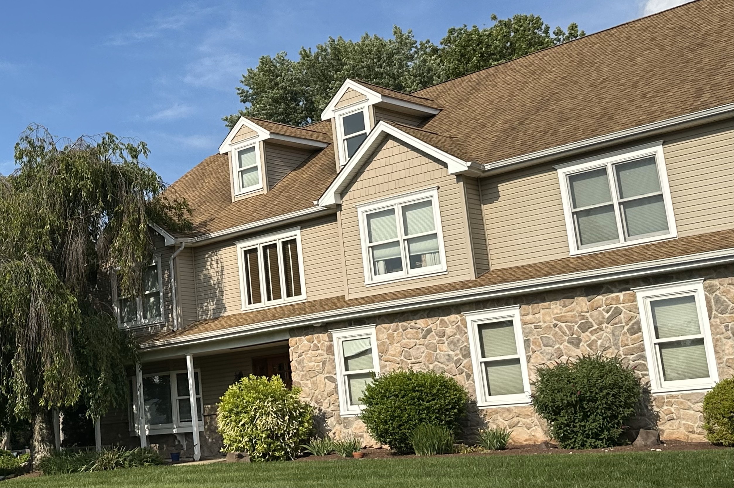 Image of house in Newtown, Pennsylvania with a deciduous tree to the left and shrubs touching the house by the front windows. Photo by J. McAdams.