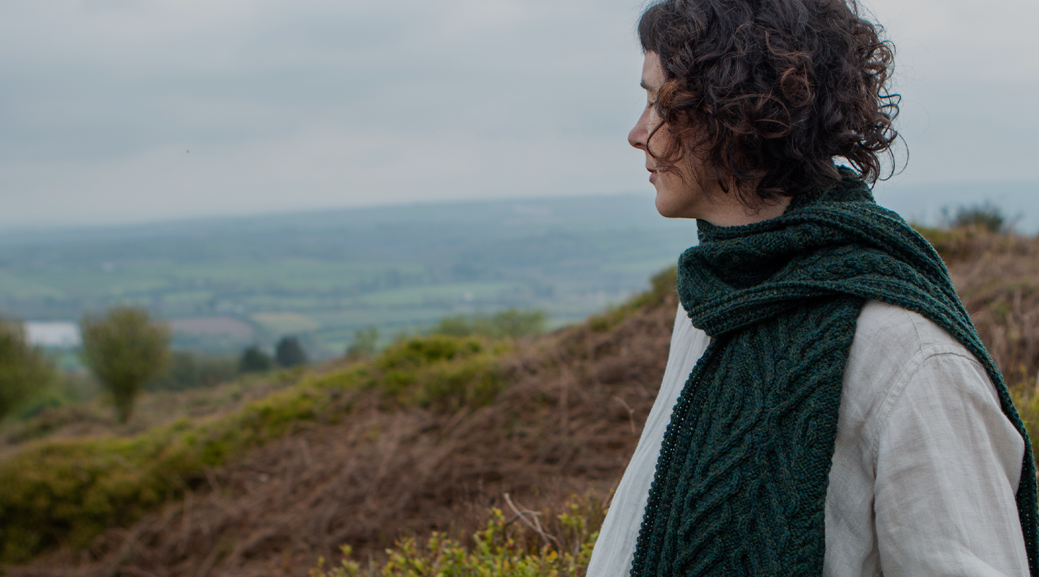 A woman wearing a hand-knit cabled scarf.