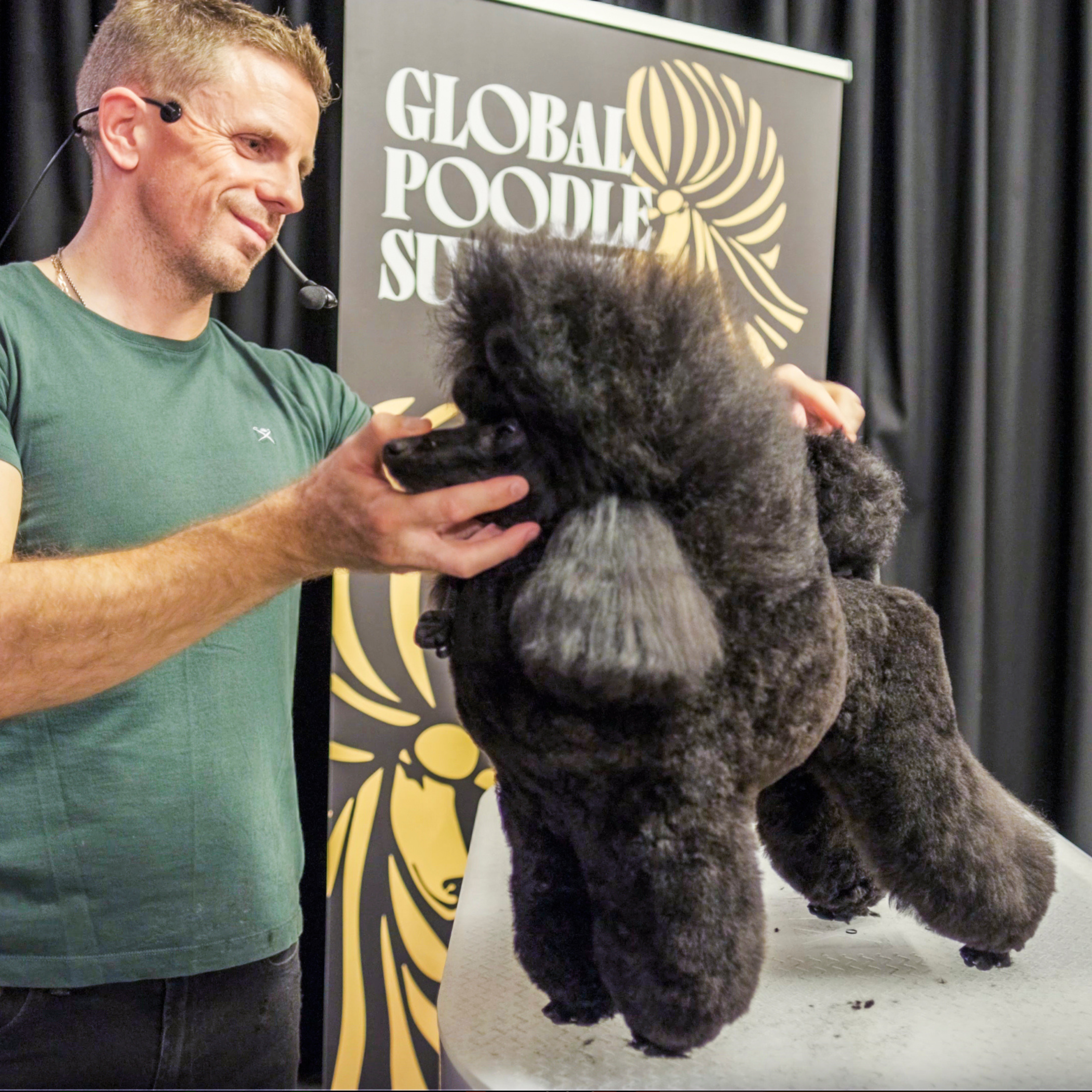 Tom Isherwood smiling, holding black Toy Poodle