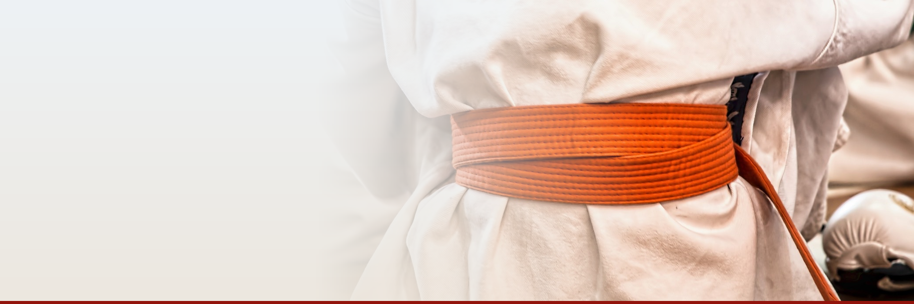 Close-up of a white dobok with an orange belt tied at the waist, representing the White and Orange Belt course on Digital Dojang