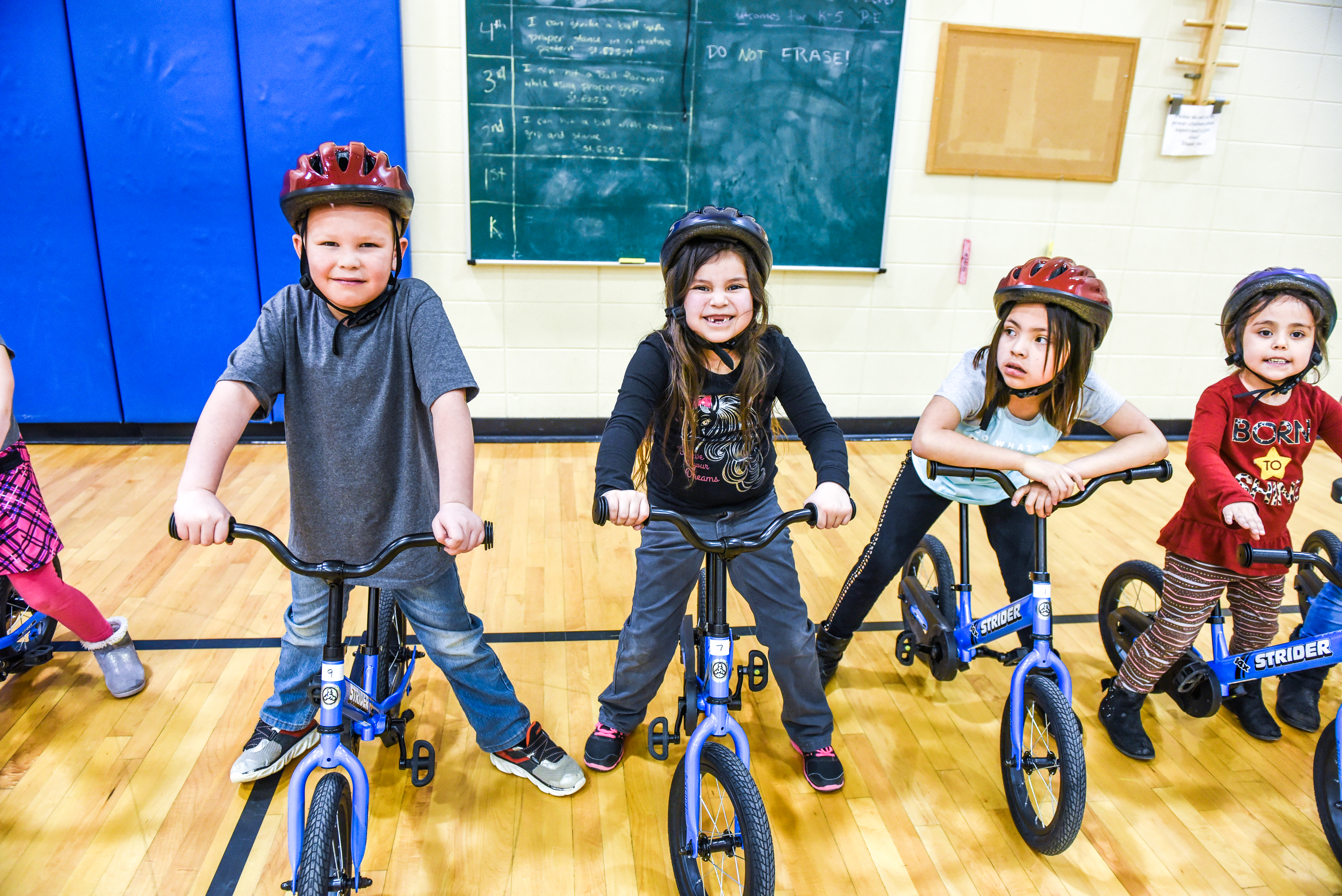 Smiling happy kids on bikes in gym class