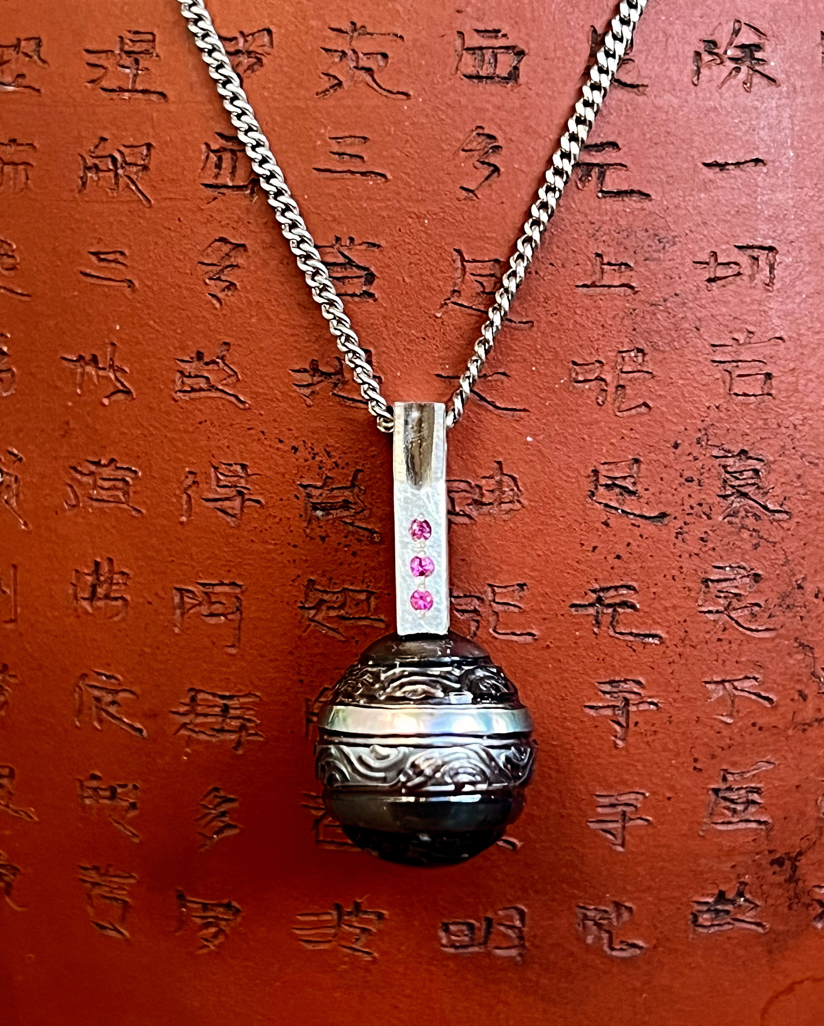 Bead set pink sapphires with a carved Tahitian pearl