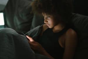 Young woman looking at a screen in bed late at night