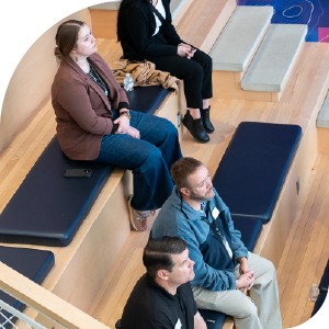 Small group of people sit in event space for onboarding presentation