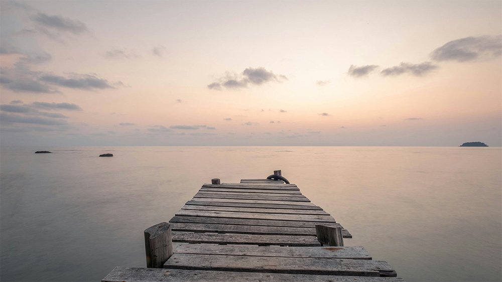 A jetty reaching out over a calm body of water, suggesting states of deep tranquility