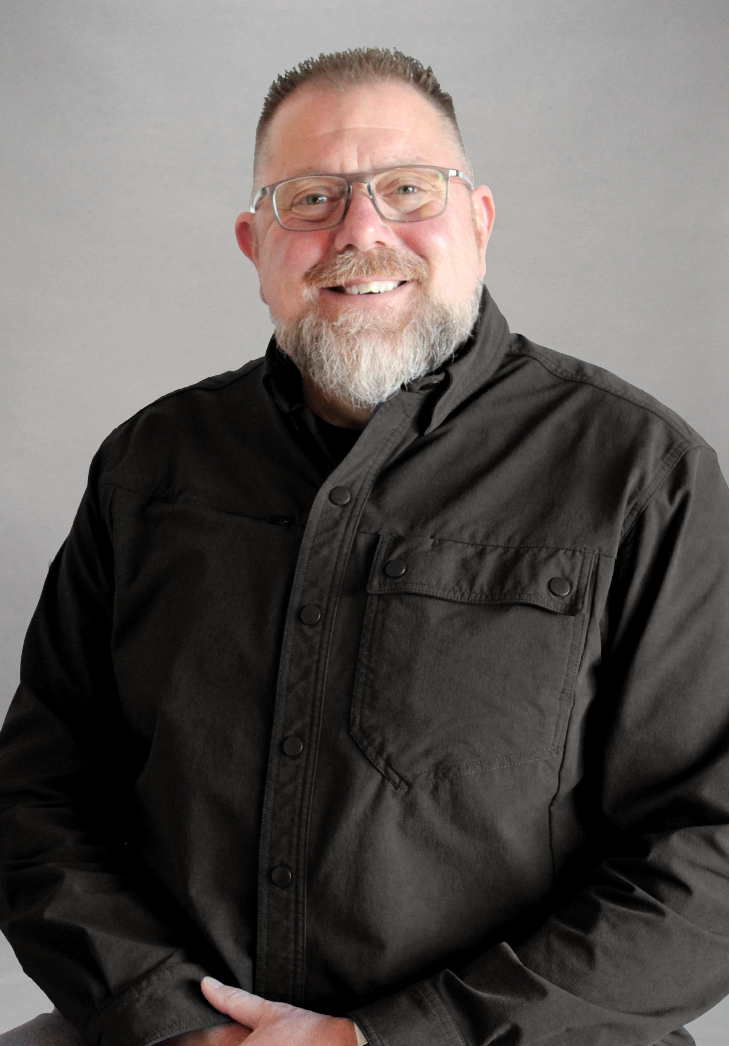 Robert Hallam smiling in a black shirt against a light gray background.