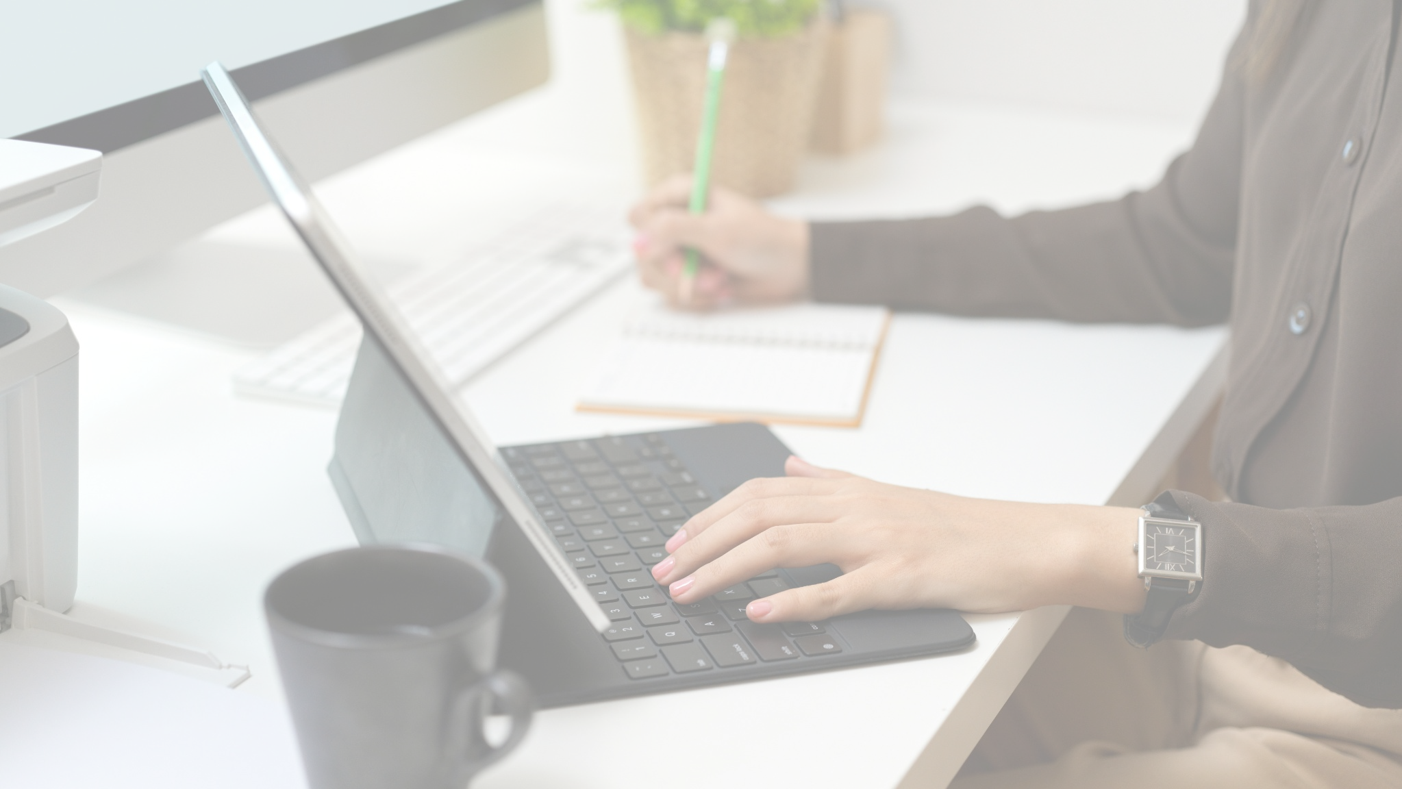 person working at laptop and making notes in planner