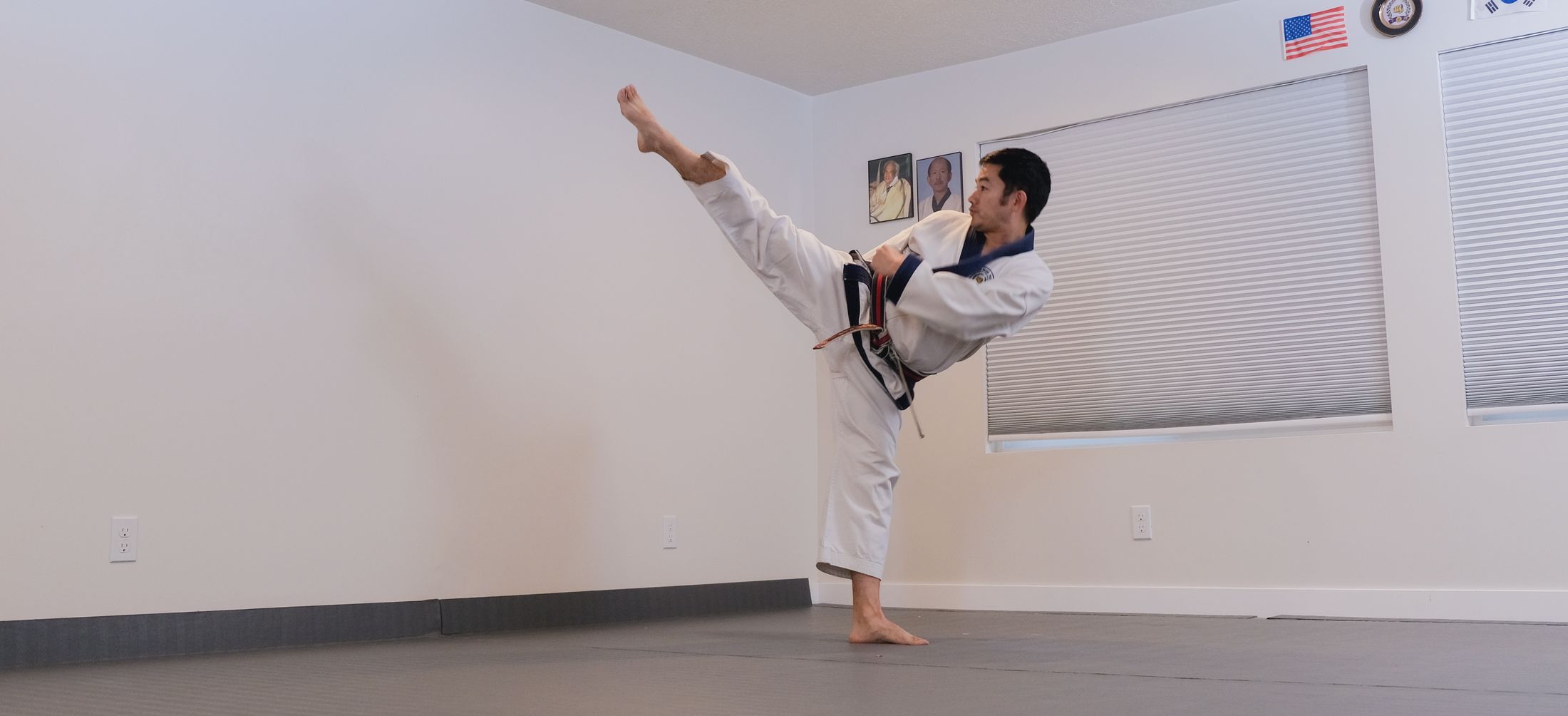 Brian Corrales holding a high side kick in the Wasatch Martial Arts Academy dojang