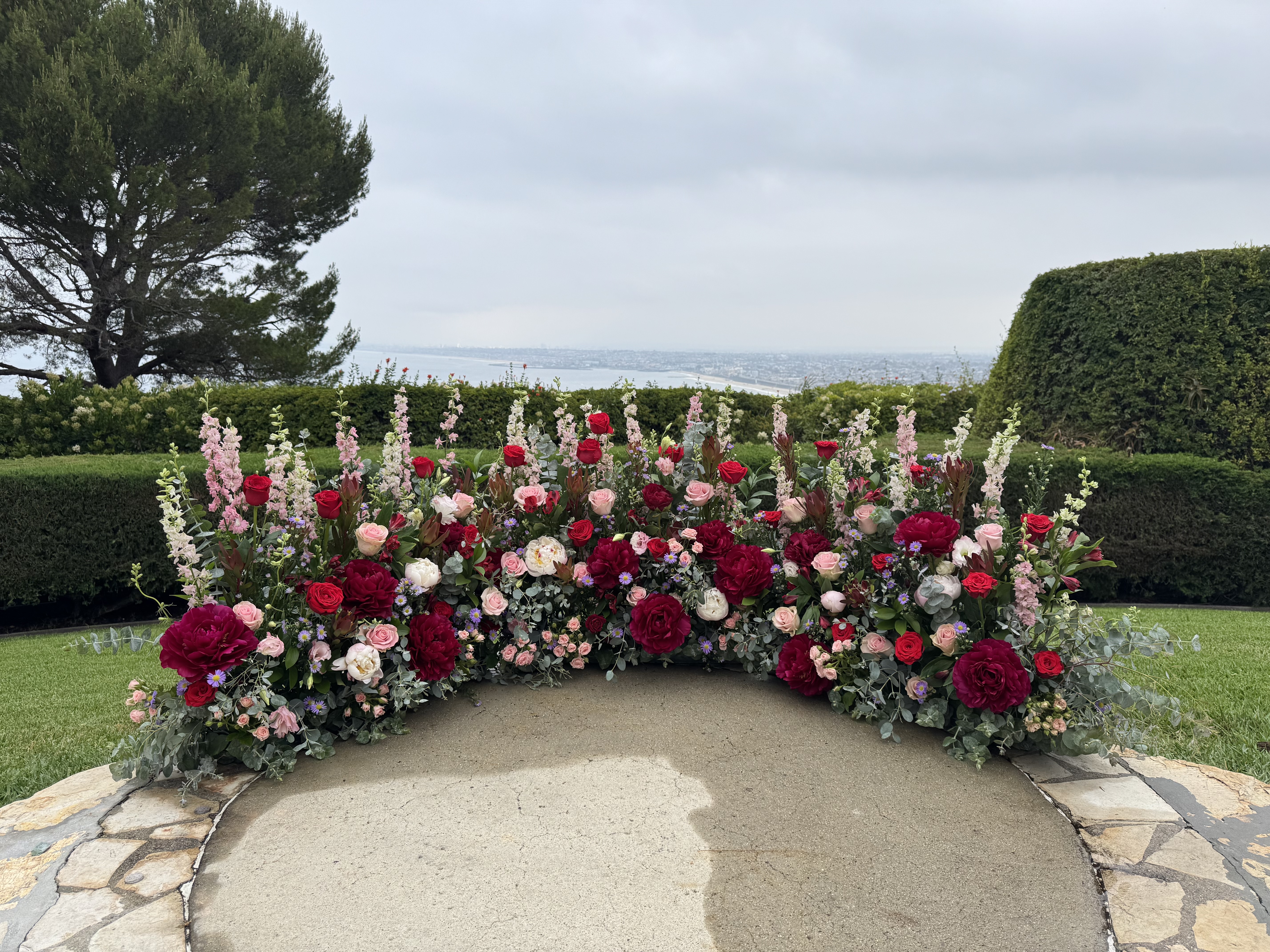 Wedding Ceremony floor decor in reds and pinks with an ocean view