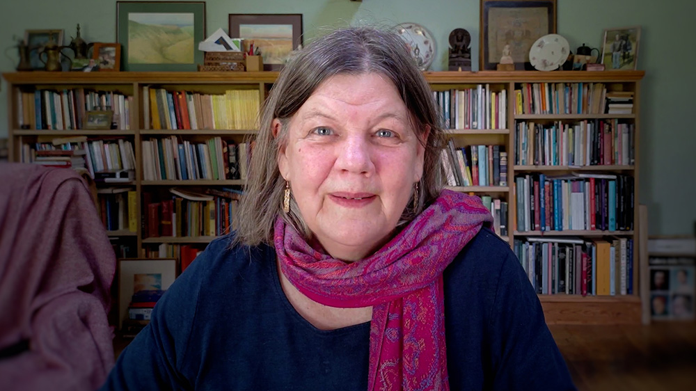 Sarah Shaw in front of a book case, smiling at the camera